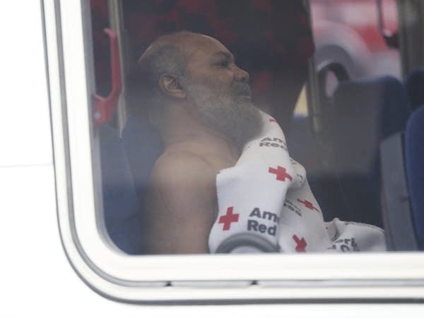 Man sitting on bus wrapped in blanket 