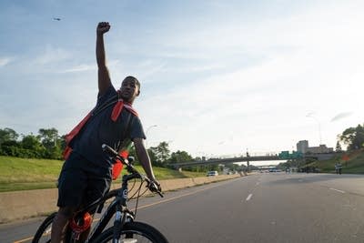 A man riding a bike throws his fist in the air.