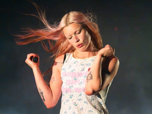 A musician sings and dances onstage in a music venue