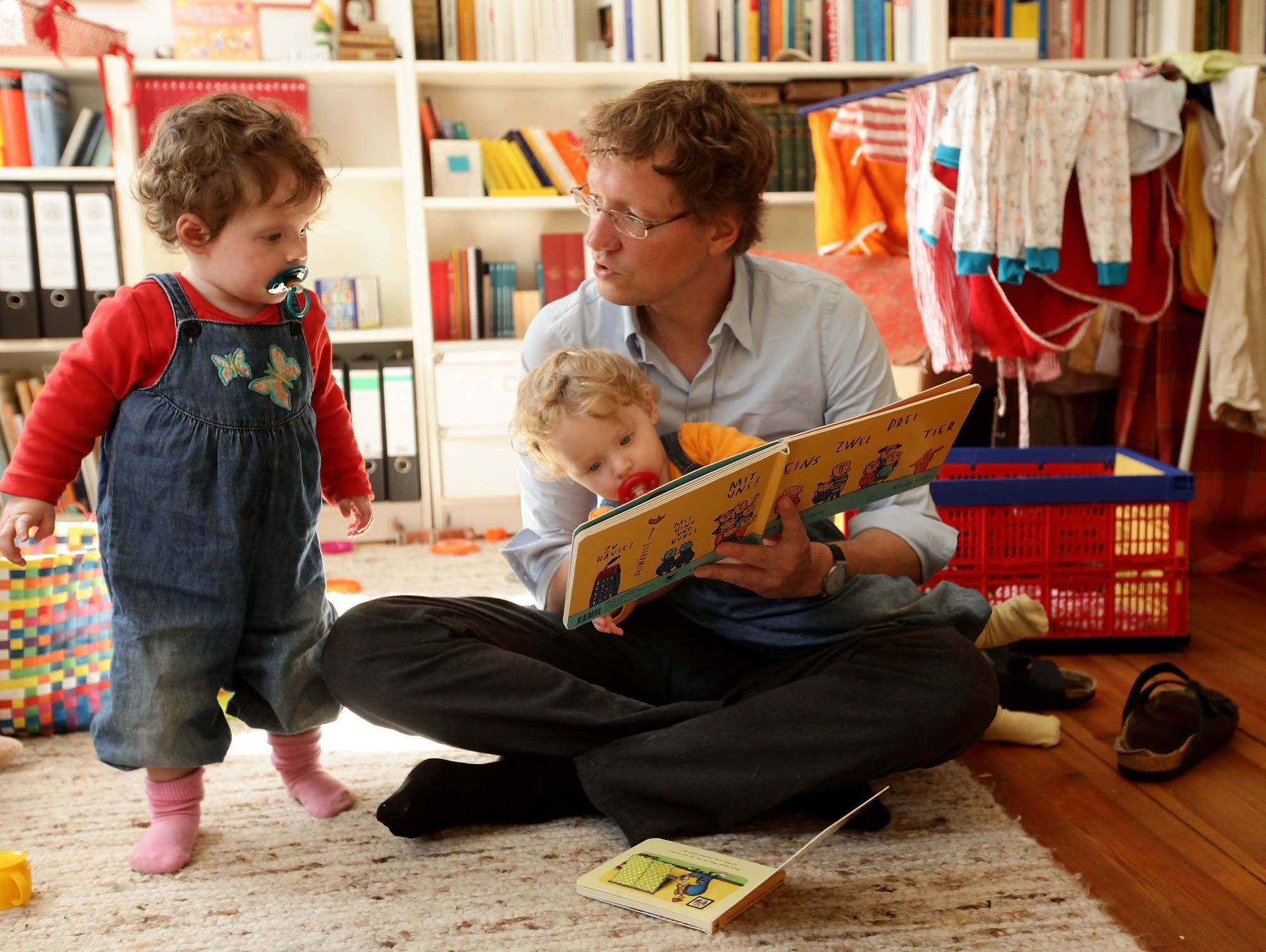 A father reads to twin daughters