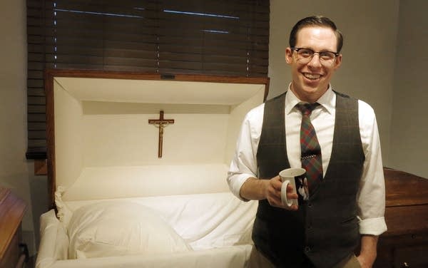 A man stands in front of a casket. 