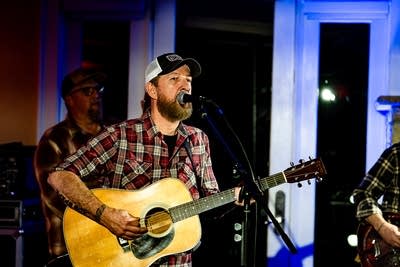 A musician sings and plays guitar onstage