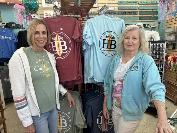 Two women pose in front of a souvenier T-shirt display