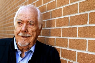 A man leans against a brick wall for a casual portrait