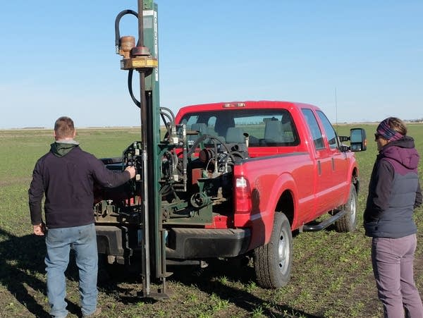 two people stand next to a truck in a field