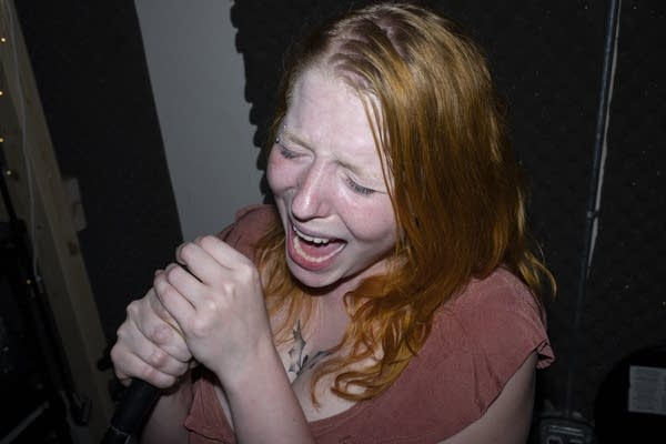 A guitarist sings into a microphone.