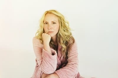 A woman poses for a photo, resting her chin on her hand