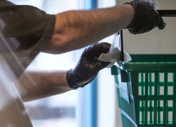 A person wearing gloves sanitizes a basket