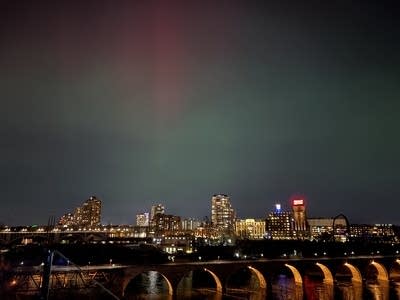 A city night scene with a view of green, red and purple lights in the sky.