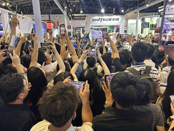 People crowded around Unitree showcasing its humanoids boxing and taking photos at the World AI Conference in Shanghai