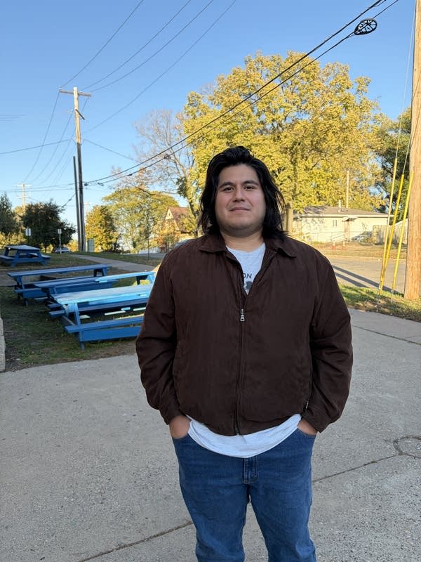 A man poses for a photo near light blue picnic tables.