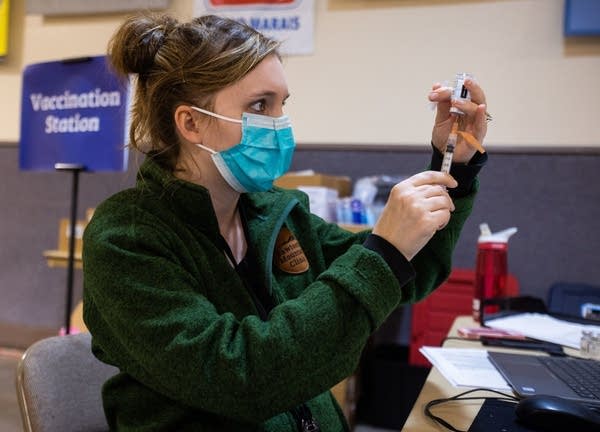 A nurse fills a syringe with a vaccine dose. 