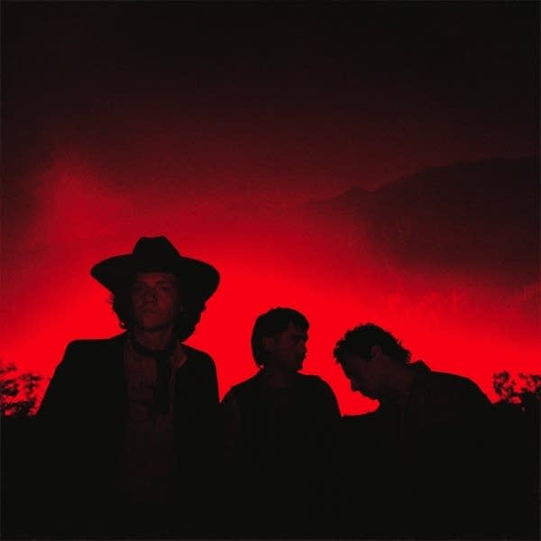 Three guys standing together against a fiery dusk