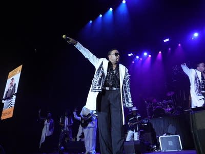 Morris Day points a microphone to the audience.