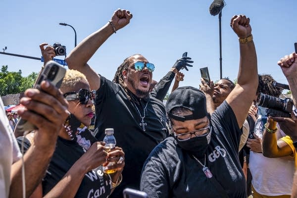 A crowd of people raise their fists. 