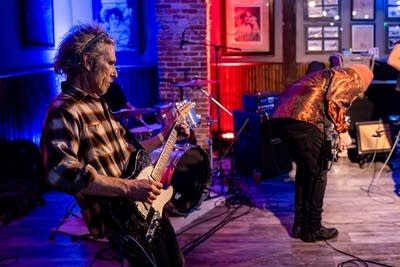 Two musicians perform onstage in a music venue