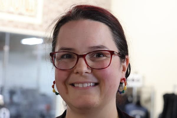 A person wears rainbow earrings