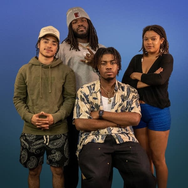 Four people pose for a photo in front of a blue background