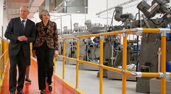 Britain's Prime Minister Theresa May (R) visits an engineering training facility in the Birmingham, central England, on November 20, 2017. British finance minister Philip Hammond is to announce £75 million ($99 million, 84 million euros) funding for Artificial Intelligence and plans to put driverless cars on UK roads by 2021. 