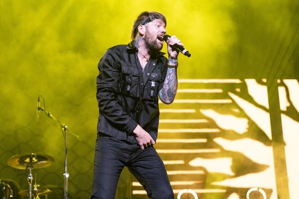 A man sings into a microphone while performing onstage