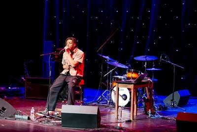 Man sitting on stool and singing on stage