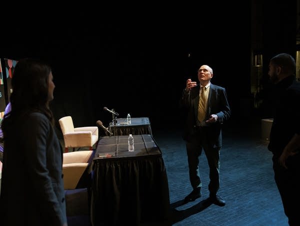 A man in a suit tosses a coin before a candidate debate