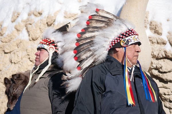 Two native mean in headdresses listen to someone speak