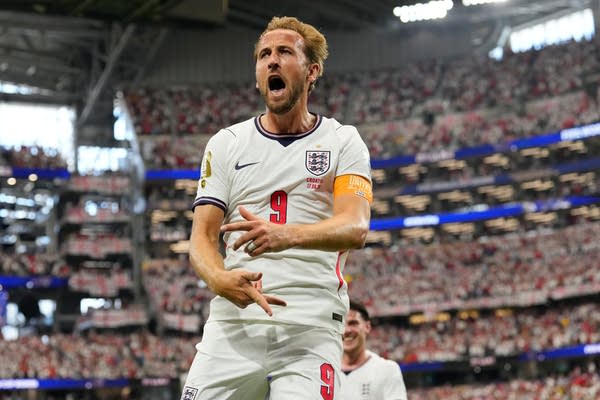 A soccer player in a white uniform celebrates a goal.