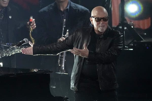 Billy Joel gestures to the band.