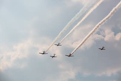 Five planes fly into a blue sky.