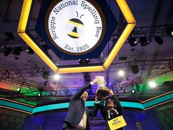 E. W. Scripps Company CEO Adam Symson (L) hands Faizan Zaki (R), 13, of Dallas, Texas, the Scripps Cup after winning in the 21st round of the 2025 Scripps National Spelling Bee at the Gaylord National Resort and Convention Center on May 29, 2025 in National Harbor, Maryland. Two hundred forty-three spellers from all over the globe ages 8 to 14 competed from May 27 to May 30, 2025 and were narrowed down to 9 finalists during the 100th anniversary of the bee.