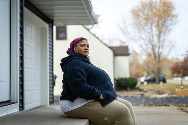 A woman sits on the front steps of a house