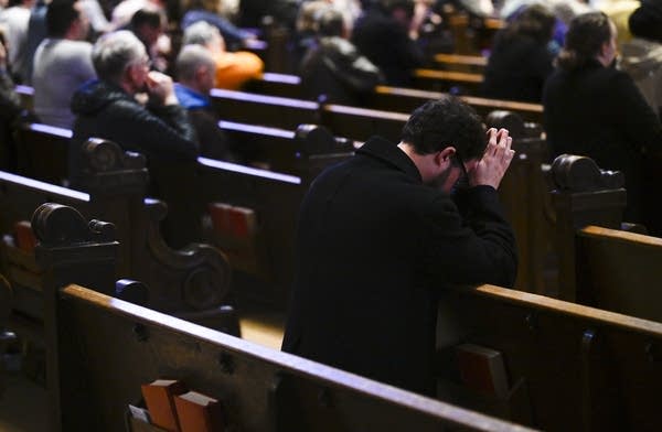 A person kneels in a pew