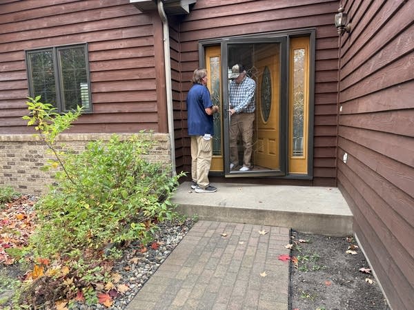 A person speaks with someone at the door