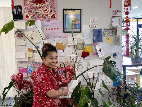 A woman stands in front of a wall covered in letters and cards