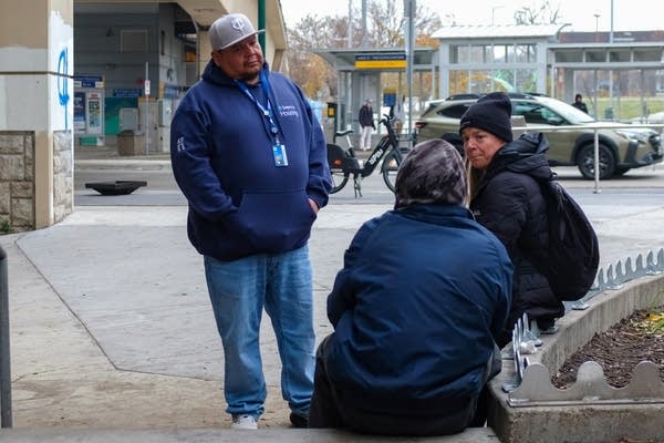 three people gathered on the street talking