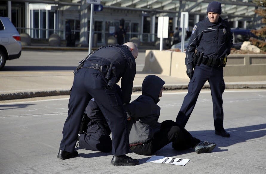 A protester is arrested for blocking the roadway.