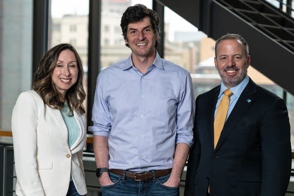 Three people stand for a posed photograph.