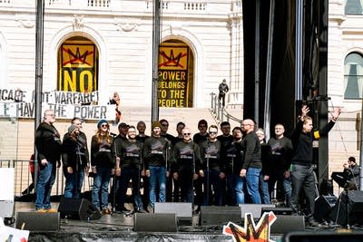 A choir singing on an outdoor stage at a large rally