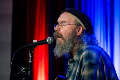 man playing acoustic guitar and singing on stage