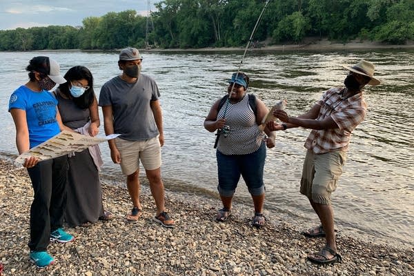 A group of people enjoy fishing by a river.