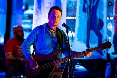 A musician plays bass onstage in a nontraditional music venue