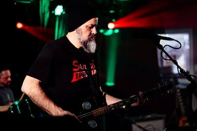 A musician plays a cigar-box guitar onstage