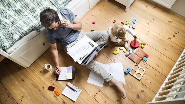 A parent makes a phone call, while taking notes.