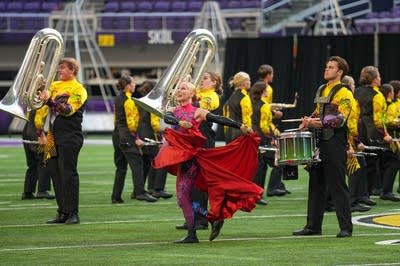 A marching band performs on the field of a football stadium.