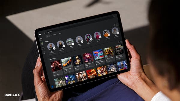 A child holds a tablet with the Roblox app interface visible.