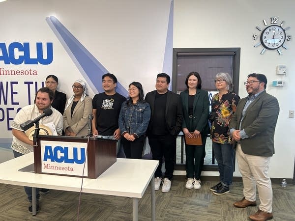 A large group stand behind a podium in an office.
