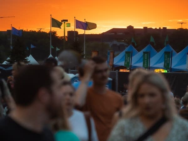 The sun sets behind a crowd of people