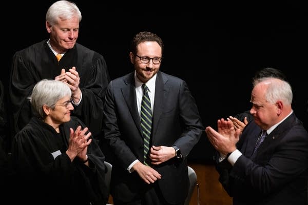 A man stands as people applaud