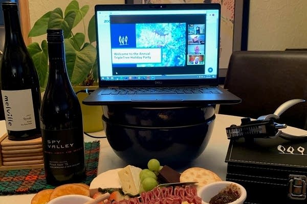 A computer screen, wine bottles and a charcuterie plate